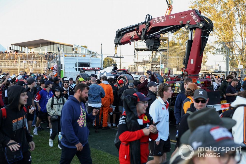 Fans invade the circuit as marshals load the car of Nyck de Vries, AlphaTauri AT04, onto a truck